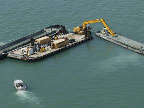 Excavator on barge dredging